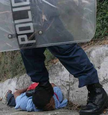 Police officer stepping on indigenous man